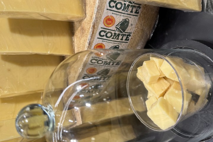 Blocks of Comté cheese with cubes in a glass container.