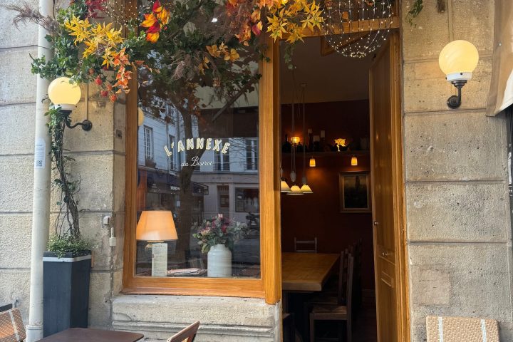 Outdoor café scene with autumn leaves and empty tables and chairs.