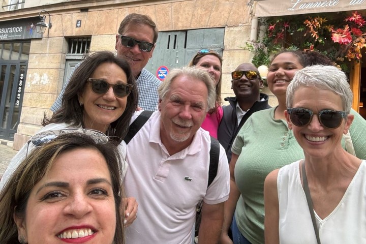 Group of people smiling outdoors in a cobblestone street.