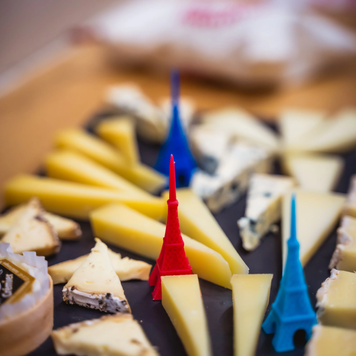 Cheese platter with Eiffel Tower toothpicks on a slate board.