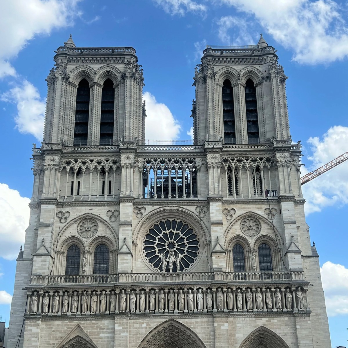 Notre-Dame Cathedral towers against a blue sky with clouds.